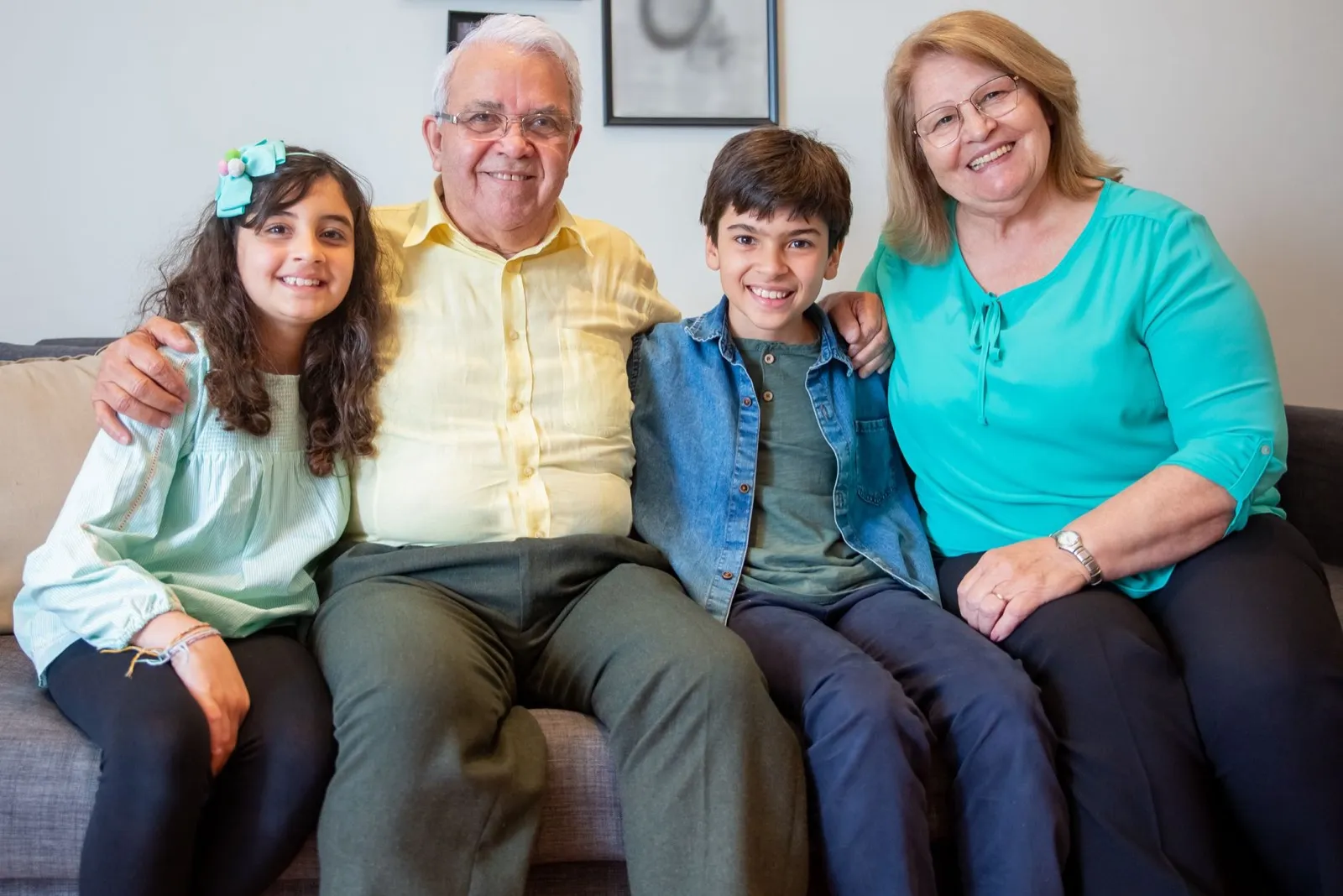 Grandparents sitting on a sofa with two grandchildren, all smiling