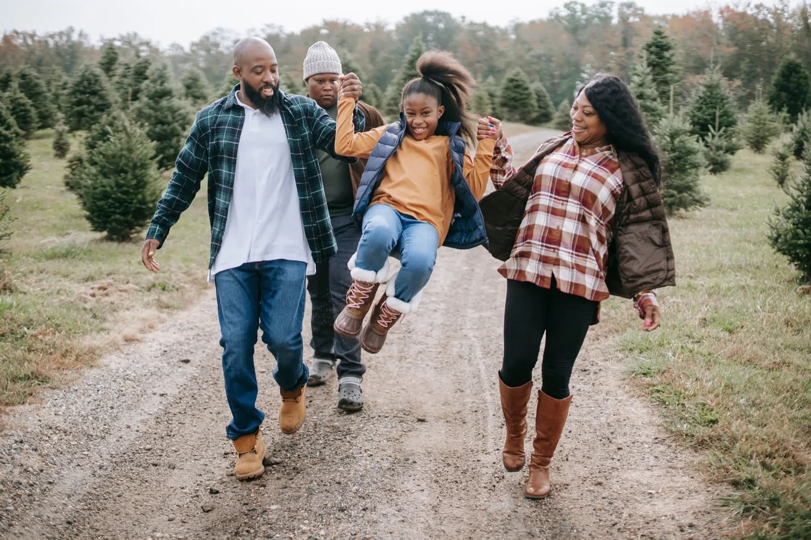 A family of four walking together along a tree-lined path, laughing.
