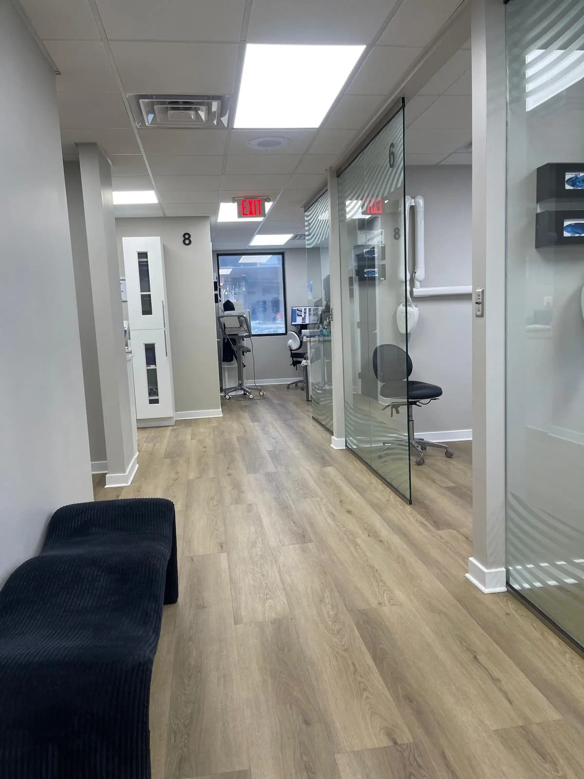 A corridor in the Stafford office, with glass-fronted treatment rooms and numbered doorways